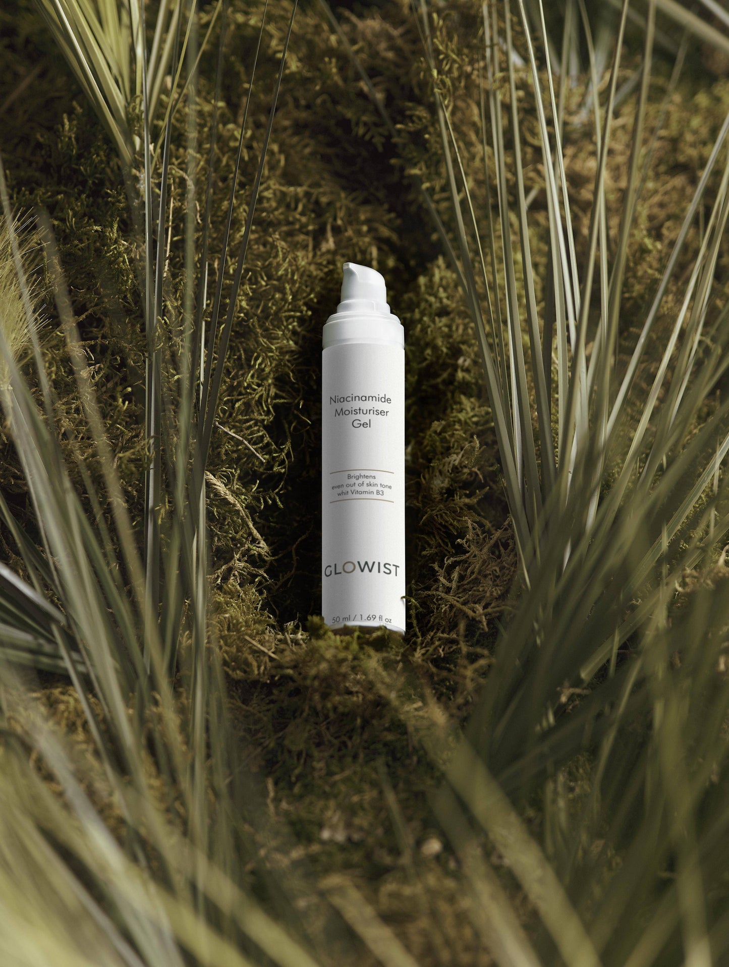 Glowist Niacinamide Moisturiser Gel bottle on green moss surrounded by grass blades